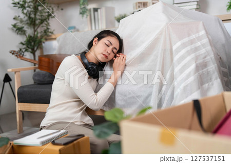 Moving and Resting. Woman taking a break while moving, resting her head on a covered object. 127537151