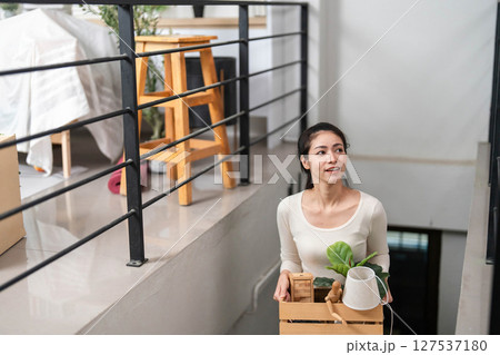Moving and Organizing. Woman carrying a box with plants up the stairs. 127537180