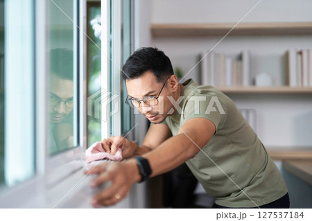 Window Cleaning by a Focused Man. Maintaining a tidy workspace. 127537184