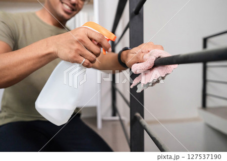 Home Cleaning and Maintenance. A man actively cleaning a railing with a spray bottle and cloth. 127537190