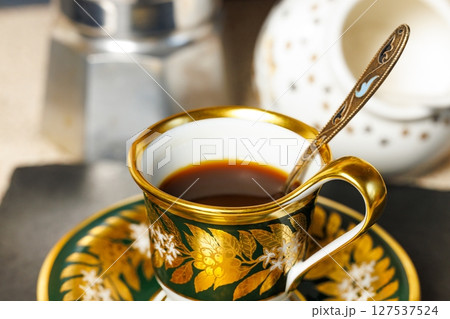 Elegant coffee cup and saucer displayed with polished spoon in a cozy cafe setting at morning light Elegant coffee cup and saucer displayed with polished spoon in a cozy cafe setting at morning light 127537524