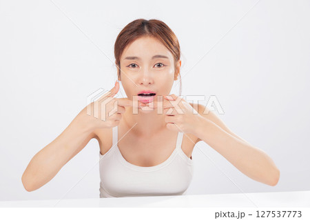 Acne removal scene where a woman squeezes acne gently, dealing with forehead blemishes, skin problems, and the reality of blackheads in a personal beauty routine. isolated studio white background Acne removal scene where a woman squeezes acne gently, dealing with forehead blemishes, skin problems, and the reality of blackheads in a personal beauty routine. isolated studio white background 127537773
