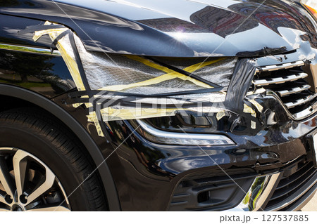 A black car that has a damaged bumper and a broken headlight A black car that has a damaged bumper and a broken headlight 127537885