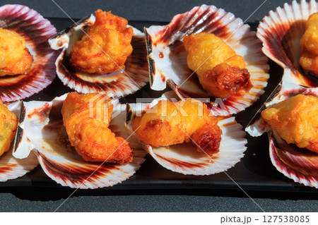 Deep-fried battered scallops in its shell on a table Deep-fried battered scallops in its shell on a table 127538085