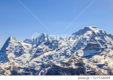 View of three famous Swiss mountain peaks Eiger, Monch and Jungfrau in the Bernese Oberland in Switzerland View of three famous Swiss mountain peaks Eiger, Monch and Jungfrau in the Bernese Oberland in Switzerland 127538094