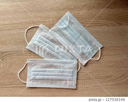 Three blue medical masks are on the table. High quality photo Three blue medical masks are on the table. High quality photo 127538149