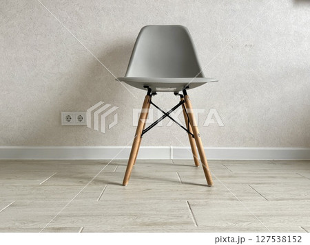 A stylish modern grey chair stands in the room opposite the wall in the apartment. High quality photo 127538152
