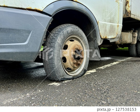The flat tire of an old truck parked on the street in summer. High quality photo 127538153