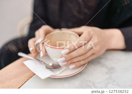 Coffee Hands Nails: Woman holds empty cup in cafe, showing white manicure after drinking. Coffee Hands Nails: Woman holds empty cup in cafe, showing white manicure after drinking. 127538252