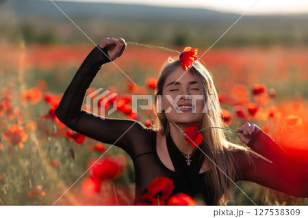 Poppy field woman summer: Girl with poppies enjoys nature's beauty in vibrant poppy field during summer. 127538309