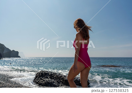 Beach Ocean Woman Summer sunbather in pink swimsuit walks on sunny beach for relaxation. 127538325
