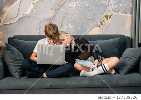 Couple Laptop Sofa - Young couple using a laptop while relaxing on a sofa in a modern home. 127538326