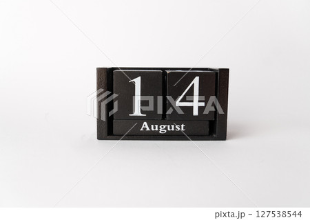 A close-up of a black wooden cube calendar that clearly displays the date "August 14th". The calendar is centered on a clean white background, highlighting its minimalist and versatile design. 127538544