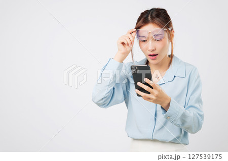 Vision loss and problem blurred with screen reading, woman holding glasses, vision affected by age, looking at mobile phone with blurry sight and bad focus. isolated studio white background Vision loss and problem blurred with screen reading, woman holding glasses, vision affected by age, looking at mobile phone with blurry sight and bad focus. isolated studio white background 127539175