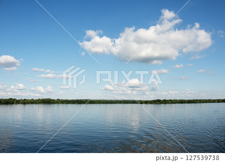 Panoramic view of the Dnieper River bank. Reflection of sky with clouds on the water surface. 127539738