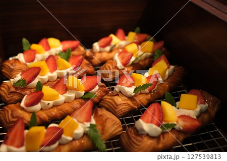 Mango pieces Strawberry tartlets with vanilla pastry cream - mini fruit tarts filled with custard vanilla pastry cream in a cookie crust. Homemade Dessert on awooden board, Vertical image. 127539813