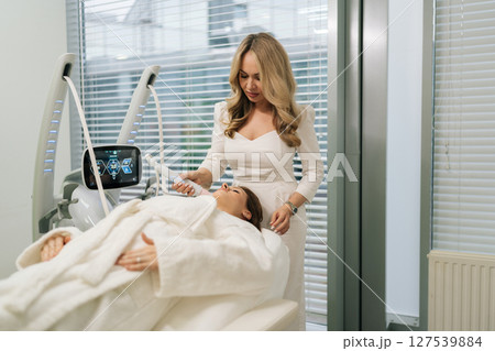 Aesthetic professional performing mesotherapy procedure on client chin, enhancing facial contours. Woman lying on treatment bed during anti-age rejuvenation skincare. Concept of beauty treatment. 127539884