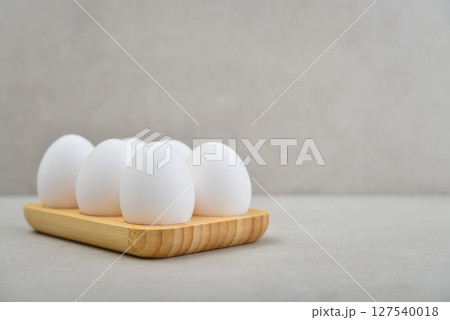 Eggs with white shell in wooden egg holder Eggs with white shell in wooden egg holder 127540018