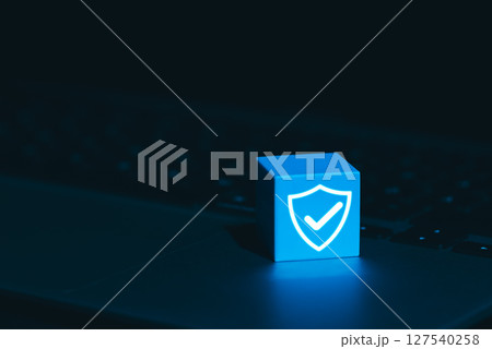 Cybersecurity and Data Protection Symbol Concept. A glowing blue cube with shield and checkmark icon on laptop keyboard, symbolizing cyber security, digital protection, trusted data security systems, 127540258