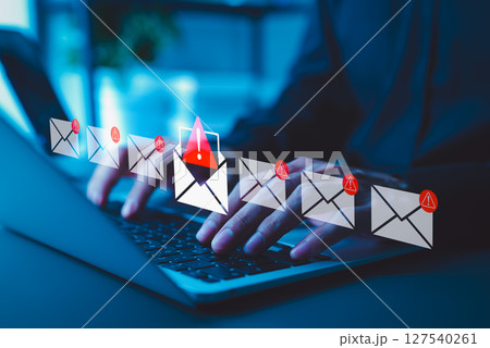 Email Security Threat Notification and Spam Warning Concept. A person using laptop with icons of mail envelopes showing red warning symbols represents potential email security threats and spam alerts. 127540261