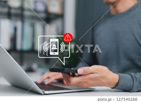 Phone scam alert notification concept. A man holding smartphone with scam warning notification, fraudulent calls, cybersecurity threats, fraud, scammer, and telecommunication security awareness. Phone scam alert notification concept. A man holding smartphone with scam warning notification, fraudulent calls, cybersecurity threats, fraud, scammer, and telecommunication security awareness. 127540266