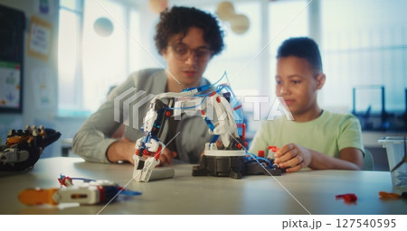 Elementary School Student Studying Model of Robotic Arm. Young Teacher Educating Boy 127540595