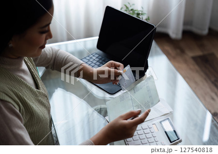 Woman holding credit card and savings account book, saving money, household expenses, monthly bills Woman holding credit card and savings account book, saving money, household expenses, monthly bills 127540818
