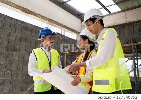 team of engineers is looking at blueprint construction and discussing them together in the construction building team of engineers is looking at blueprint construction and discussing them together in the construction building 127540852