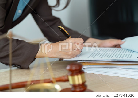 Legal Professional Signing Documents. A lawyer writing notes at a desk with legal papers and a gavel. Legal Professional Signing Documents. A lawyer writing notes at a desk with legal papers and a gavel. 127541020