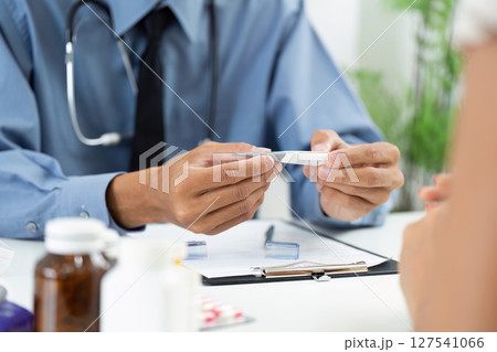 Thermometer Check. Doctor examining patient's temperature during consultation. Thermometer Check. Doctor examining patient's temperature during consultation. 127541066