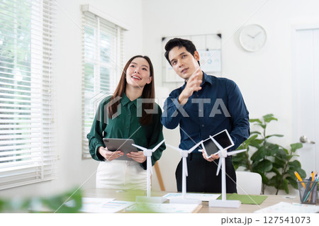 Team Collaboration. Professionals discussing ESG initiatives with wind turbine models. 127541073