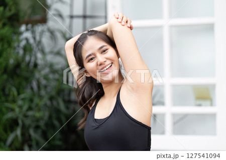 Wellness and Fitness. Young woman stretching and smiling outdoors, promoting healthy lifestyle and self-care. 127541094