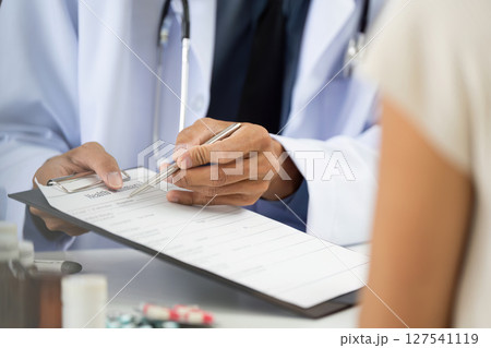 Healthcare Consultation. Doctor reviewing patient health information on clipboard. 127541119