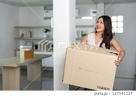 Moving Day: Woman Carrying Box with Joy in New Home Moving Day: Woman Carrying Box with Joy in New Home 127541127