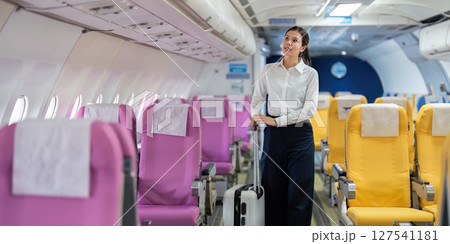 Business travel and personal luggage. A woman with a suitcase walking through an airplane aisle. 127541181