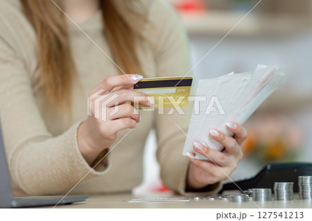 Credit Card Use and Financial Management. Woman comparing receipts with credit card in hand. 127541213