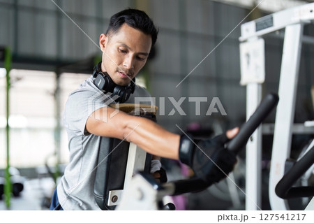 Fitness Training. Male athlete adjusting gym equipment in modern fitness center. 127541217