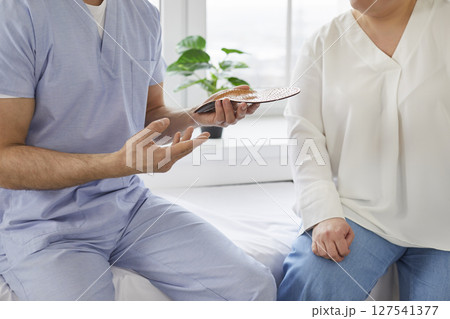 Doctor advises patient about individual orthopedic insoles for correction of flat feet. 127541377