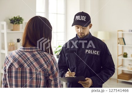 Police officer taking notes while interrogating witness, victim or suspect of crime Police officer taking notes while interrogating witness, victim or suspect of crime 127541466