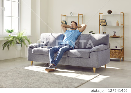 Young relaxed man sitting on the sofa in the living room at home and having a rest. 127541493