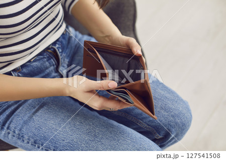 Woman who is experiencing a financial crisis opens her empty wallet with no money Woman who is experiencing a financial crisis opens her empty wallet with no money 127541508