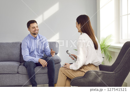 Young woman with microphone interviewing smiling successful businessman 127541521
