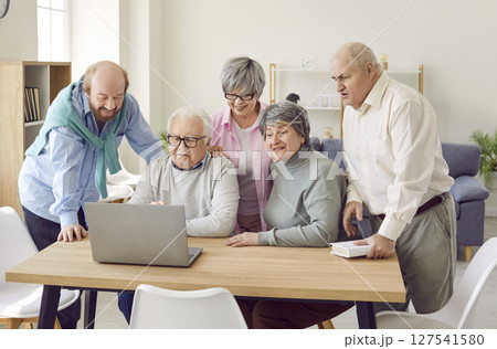 Group of senior people in retirement home using laptop computer and watching movie 127541580