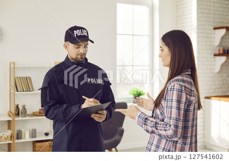 Policeman interviewing woman witness after burglary at crime scene 127541602