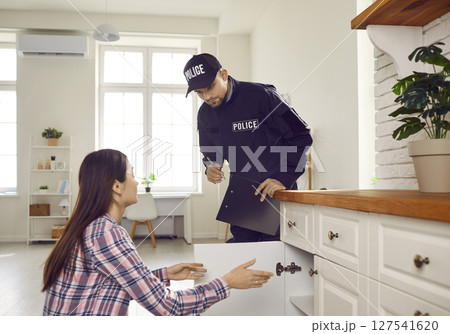 Woman house owner showing policeman her kitchen and telling what things are gone Woman house owner showing policeman her kitchen and telling what things are gone 127541620