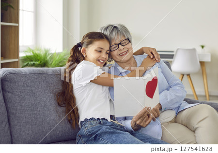 Happy grandmother receives a handmade birthday card from her little loving granddaughter 127541628