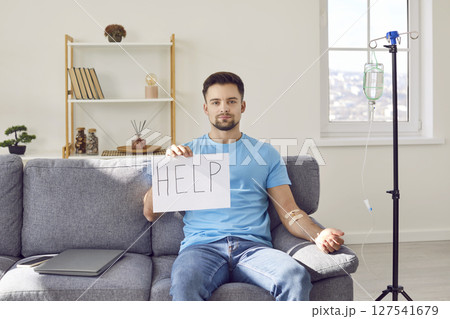 Sick young man getting intravenous IV line medical infusion therapy and asking for help 127541679