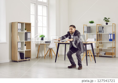 Business man in a suit doing physical exercises during a break at work in the office 127541721