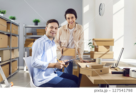 Young happy colleagues looking at camera at workplace in storeroom checking stock and inventory 127541798