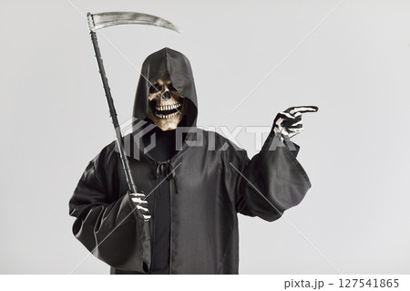 Portrait of creepy man in image of death with scythe pointing his finger to side. Portrait of creepy man in image of death with scythe pointing his finger to side. 127541865